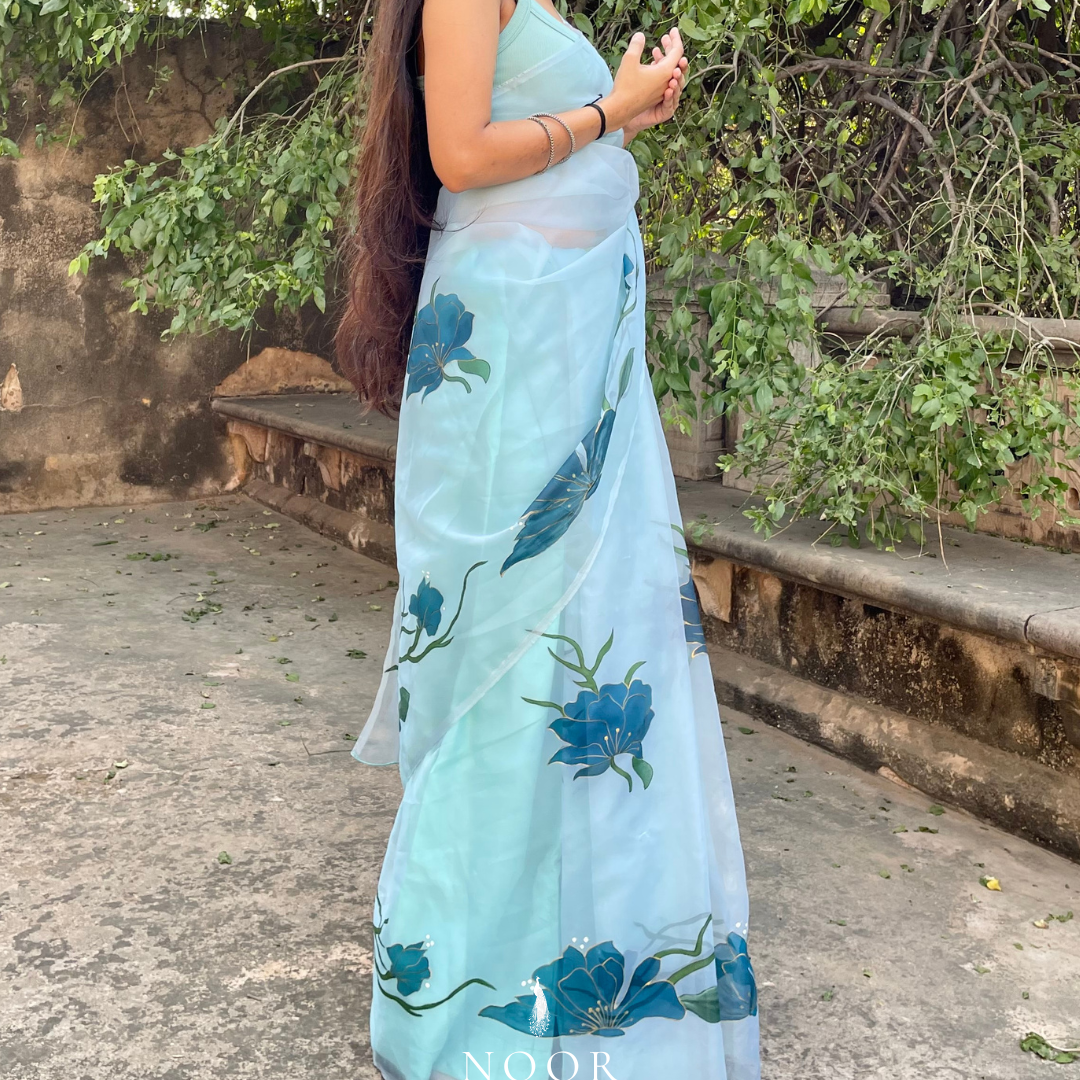hand painted saree in pure organza silk by noor by hansa in teal colour paired with a pure cotton blouse piece, shells on the pallu