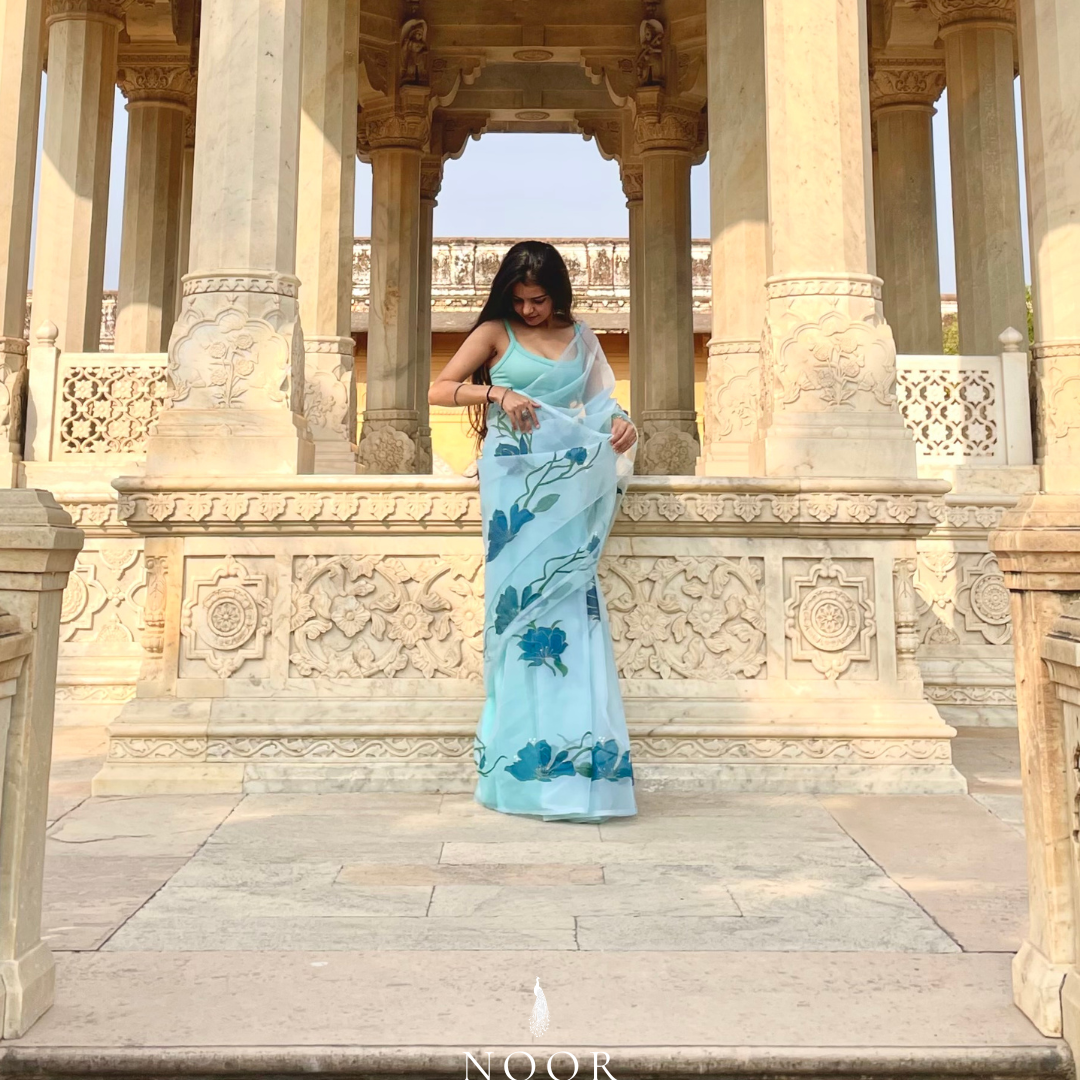 hand painted saree in pure organza silk by noor by hansa in teal colour paired with a pure cotton blouse piece, shells on the pallu