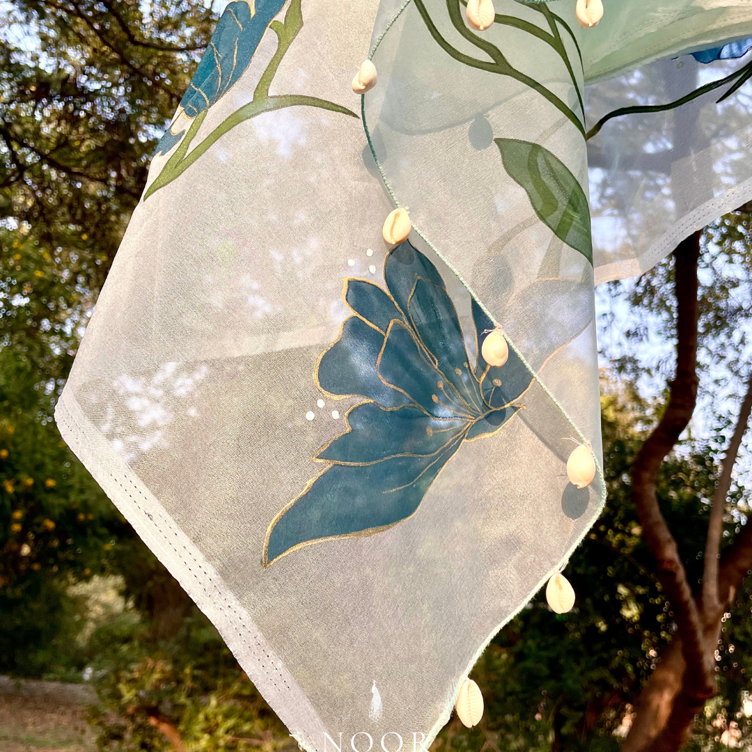 hand painted saree in pure organza silk by noor by hansa in teal colour paired with a pure cotton blouse piece, shells on the pallu