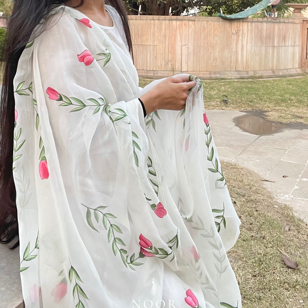 hand painted ivory 'jaituni' odhani in pure organza silk fabric with hand-painted motifs of leaves & pink tulips spread all over, embellished with studded stones. light and flowy, this makes for a perfect summer essential