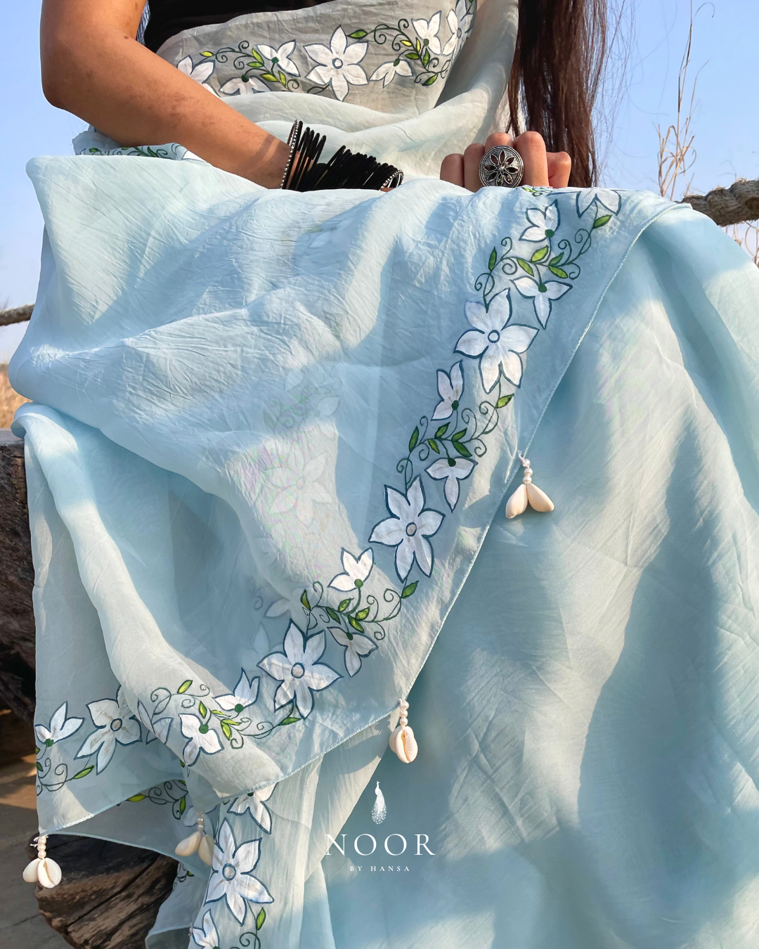 hand painted saree in pure organza silk by noor by hansa in blue colour paired with a pure cotton blouse piece, shells on the pallu