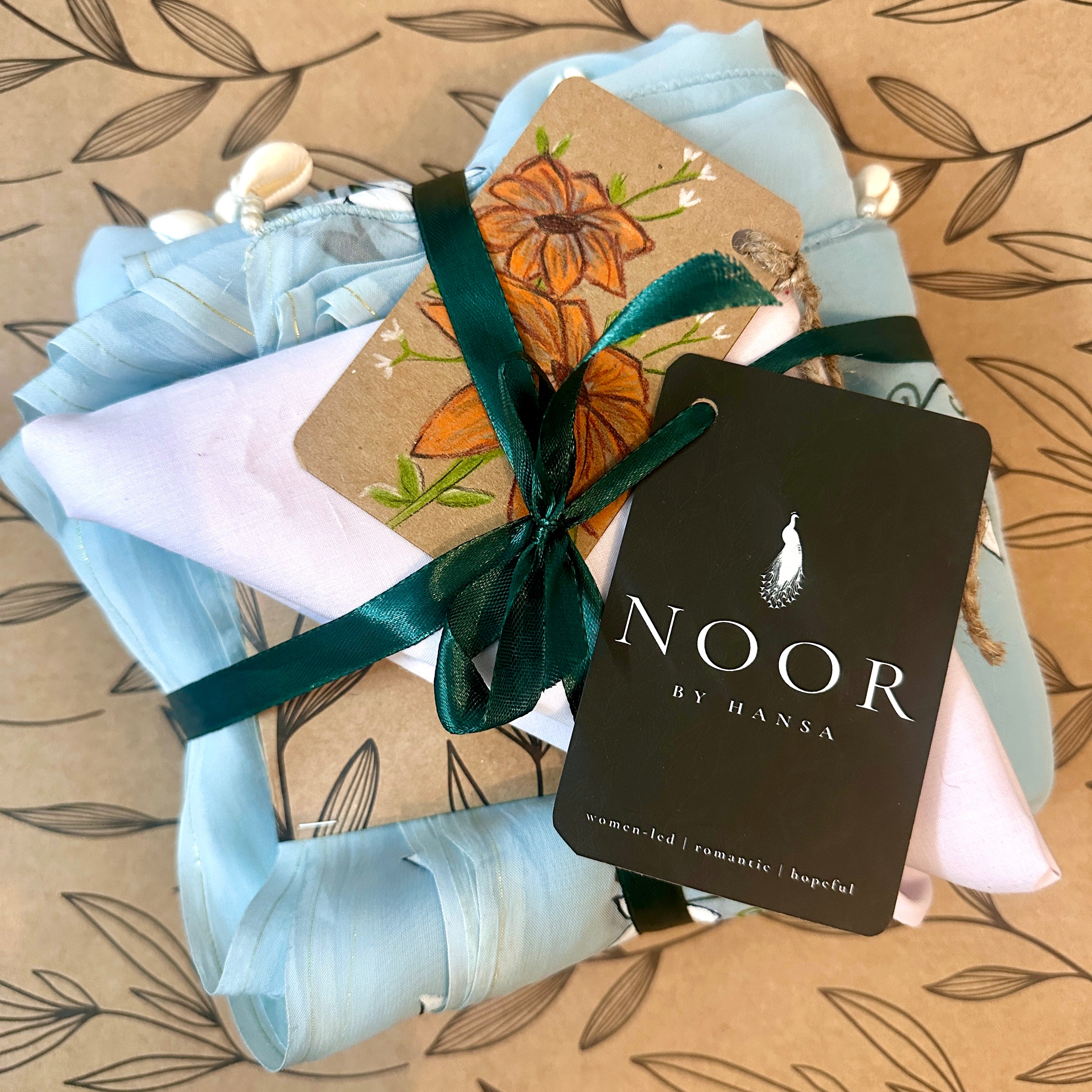 hand painted saree in pure organza silk by noor by hansa in blue colour paired with a pure cotton blouse piece, shells on the pallu packaging