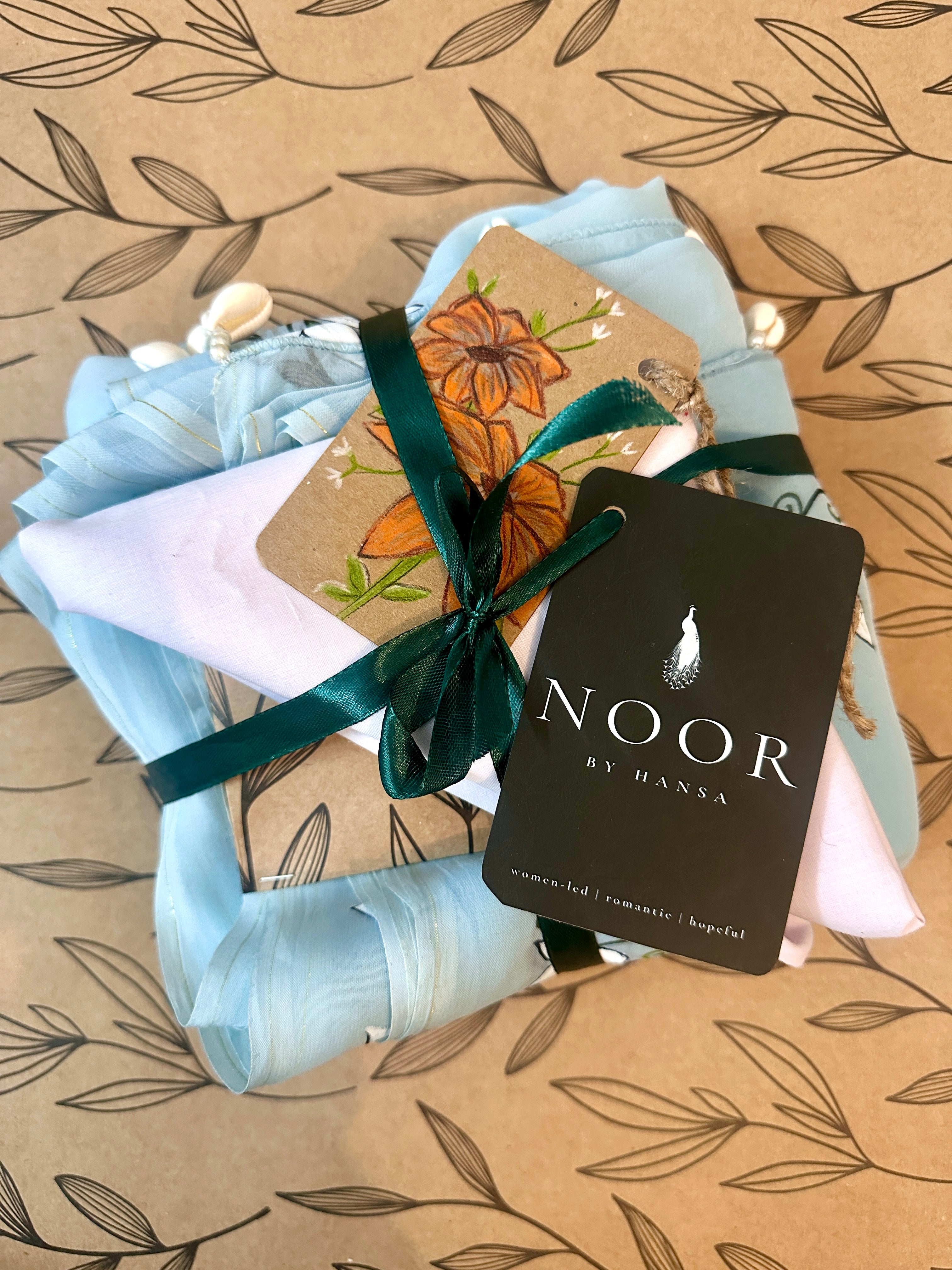 hand painted saree in pure organza silk by noor by hansa in blue colour paired with a pure cotton blouse piece, shells on the pallu packaging