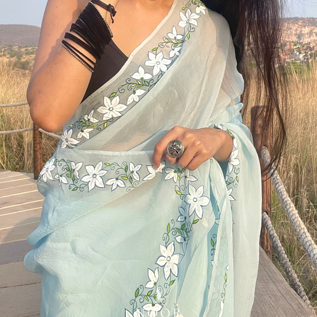 hand painted saree in pure organza silk by noor by hansa in blue colour paired with a pure cotton blouse piece, shells on the pallu