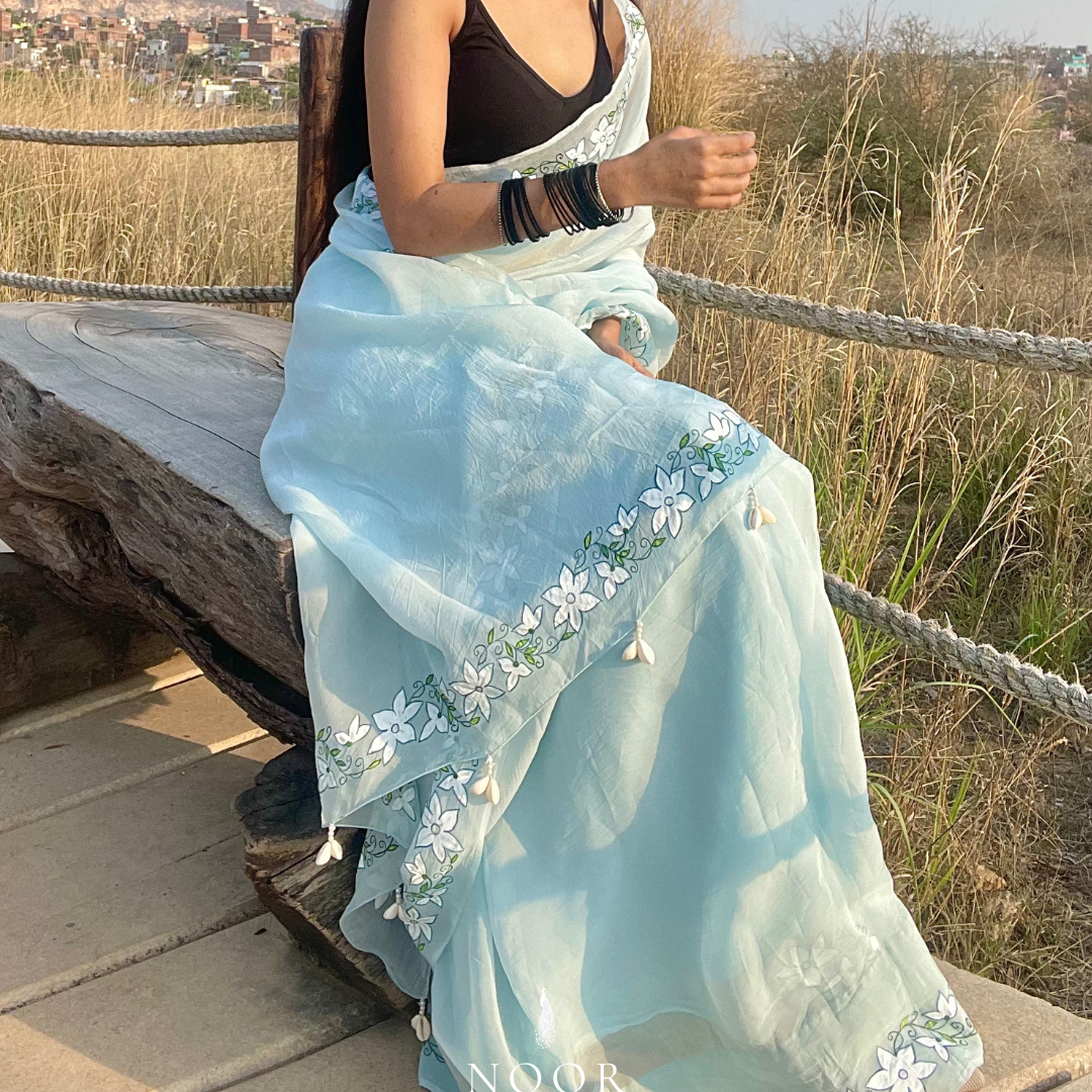 hand painted saree in pure organza silk by noor by hansa in blue colour paired with a pure cotton blouse piece, shells on the pallu
