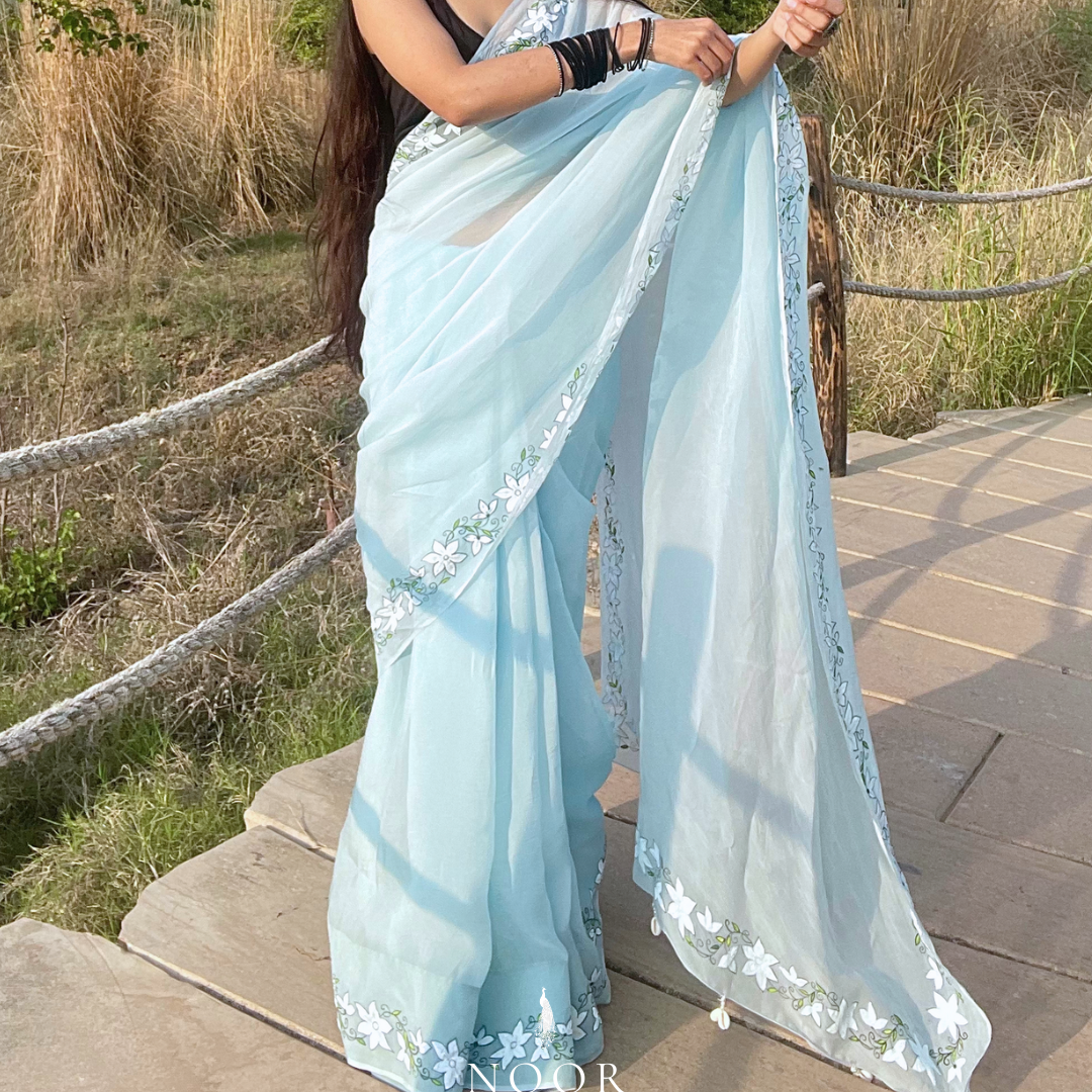 hand painted saree in pure organza silk by noor by hansa in blue colour paired with a pure cotton blouse piece, shells on the pallu