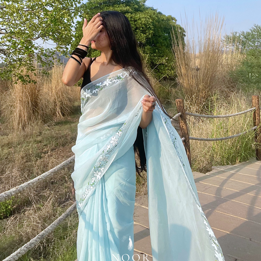 hand painted saree in pure organza silk by noor by hansa in blue colour paired with a pure cotton blouse piece, shells on the pallu
